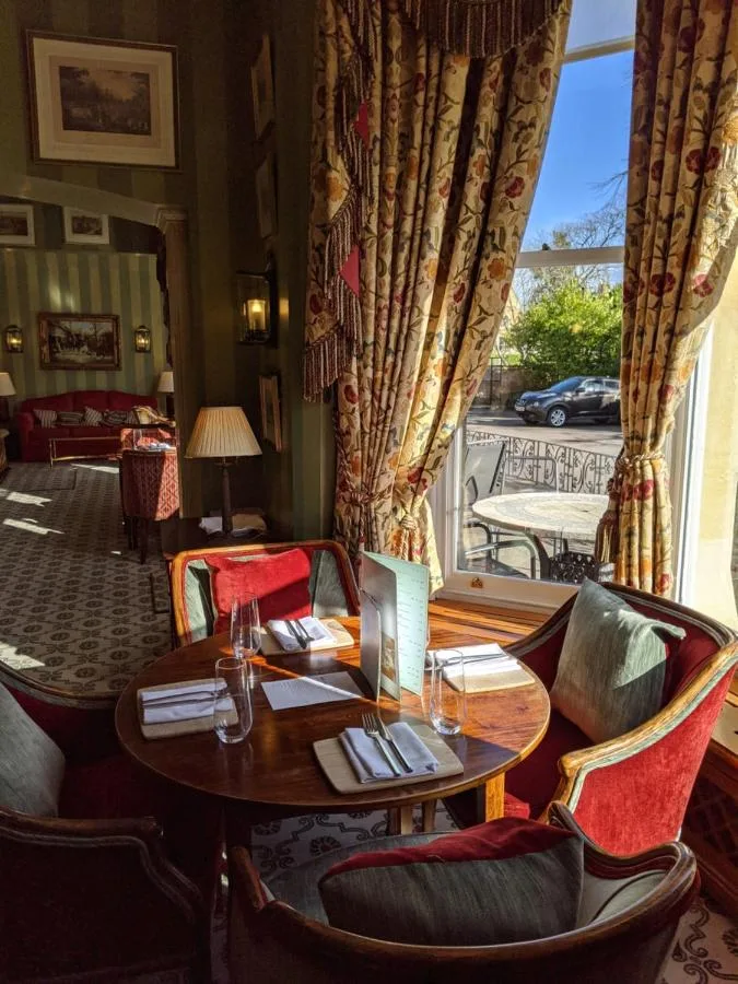 Tables and chairs by the window in the dining room at Cotswold Lodge Hotel