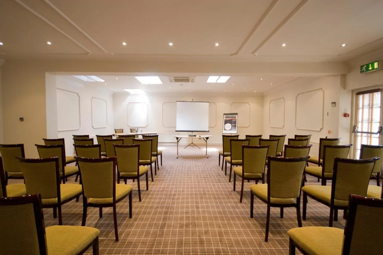 An empty meeting room with chairs and a whiteboard at Cotswold Lodge Hotel
